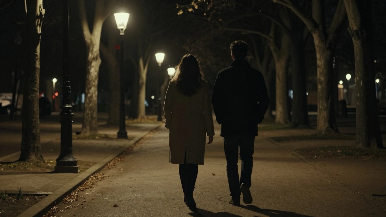 Un couple marchant en silence dans le parc de Bercy la nuit, silhouetté sous les lampes anciennes, une feuille rouge flottant entre eux.